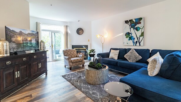 A modern living room with a dark wood cabinet, a blue sofa, a patterned armchair, and a round coffee table.
