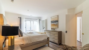 A bedroom with a bed, bedside lamp, dresser, and a painting on the wall.