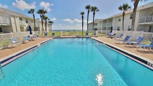 A swimming pool with clear blue water, surrounded by lounge chairs and palm trees. - Couples Retreat at Colony Beach Club (New Smyrna Beach)
