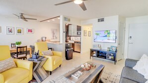 A modern living room with yellow armchairs, a grey sofa, a coffee table, and a flat-screen TV. - Couples Retreat at Colony Beach Club (New Smyrna Beach)
