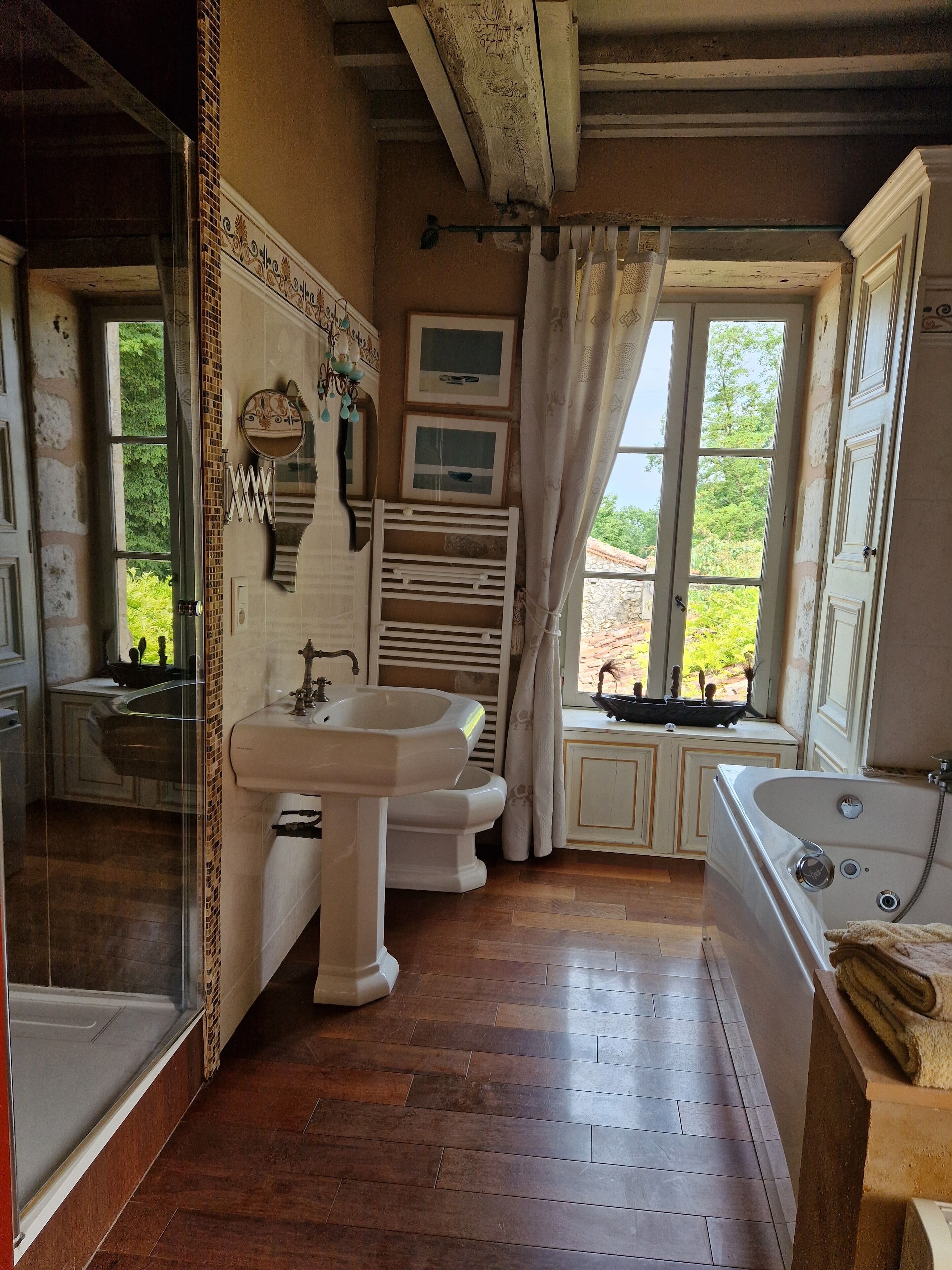 A bathroom with a bathtub, a sink, and a window with curtains.