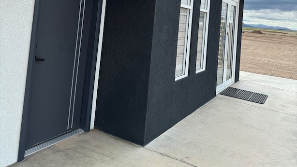 A modern building with a dark facade, large windows, and a garage door. - REL-X INN (Ahumada)
