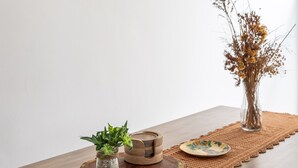 A wooden table with a woven placemat, a small potted plant, a wooden bowl, and a vase with dried flowers. - 3 minutes from Leme beach | GS501 (Rio de Janeiro)