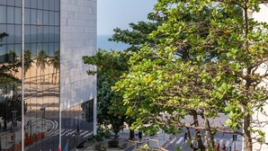 A modern building with a glass facade, a street with cars, and flags. - 3 minutes from Leme beach | GS501 (Rio de Janeiro)