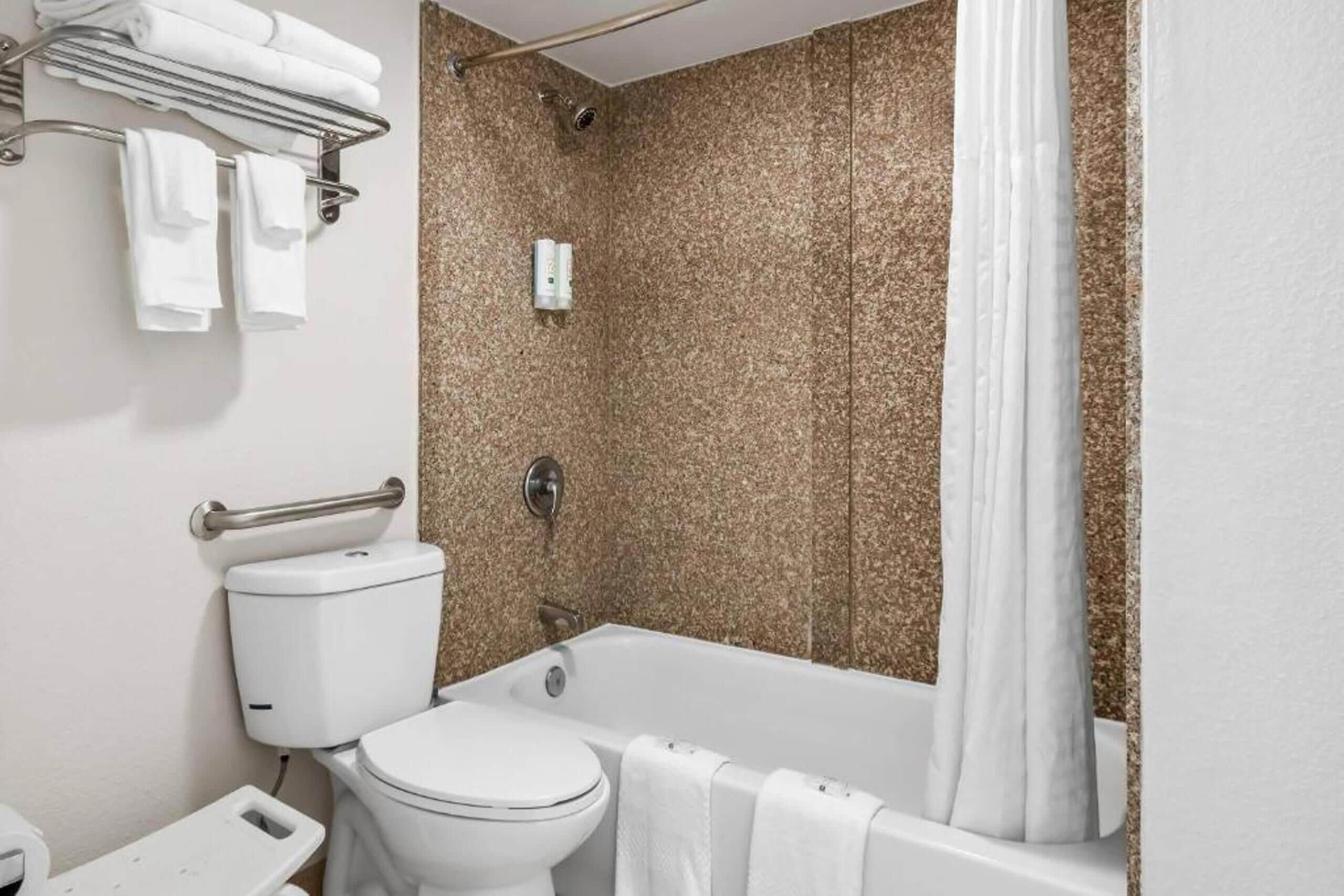 Une salle de bain moderne équipée de toilettes, d’une baignoire et d’un rideau de douche.