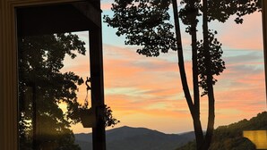 A view from a window overlooking a mountainous landscape with trees and a sunset. - The Camp - Luxe Blue Ridge Condo (Burnsville)