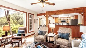 A cozy living room with a fireplace, wooden beams, and a view of the outdoors. - The Camp - Luxe Blue Ridge Condo (Burnsville)