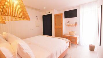A bedroom with a bed, a wooden desk, a chair, a hanging lamp, and a window with curtains.