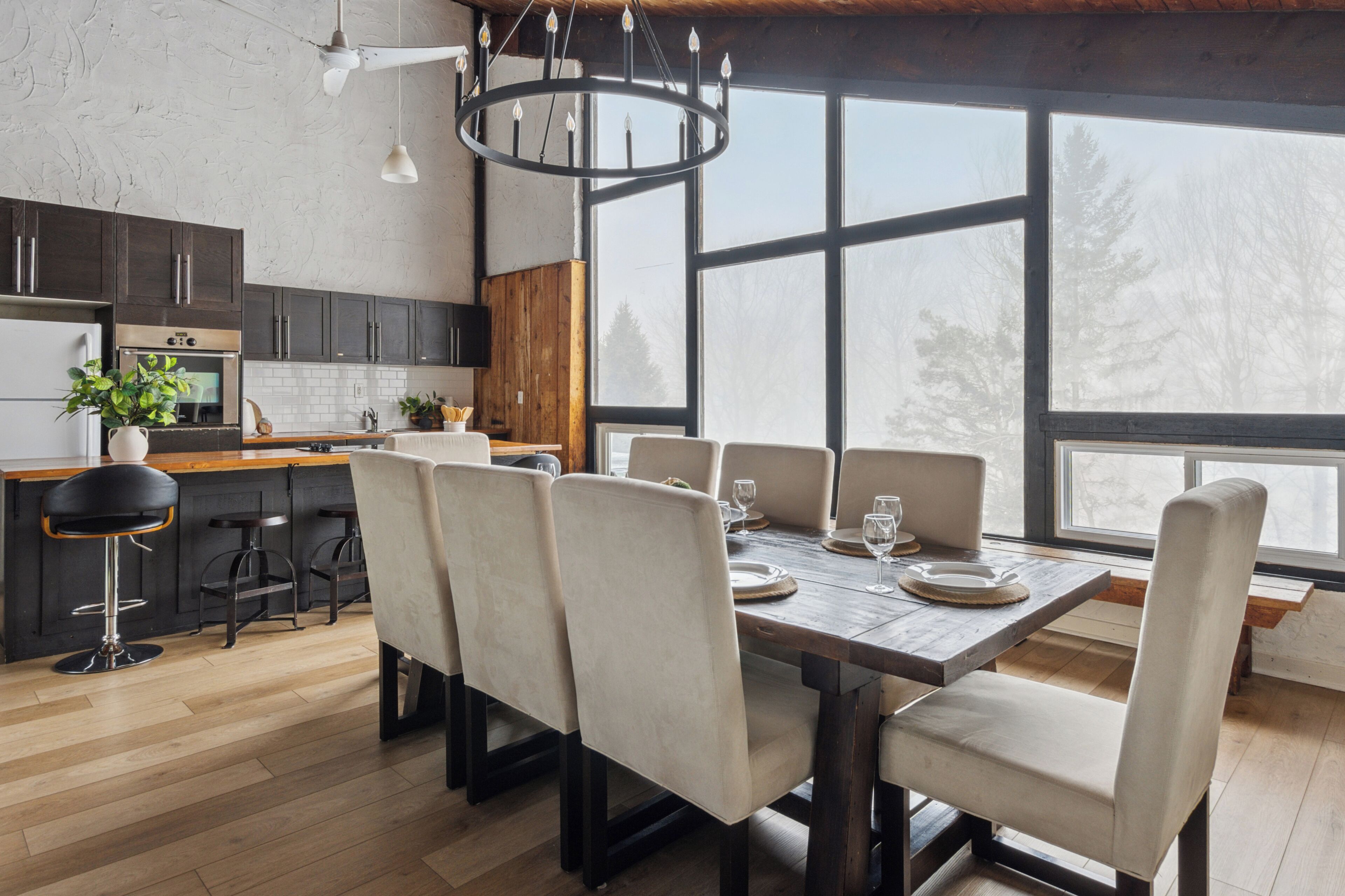 A modern kitchen with dark cabinets, a wooden countertop, and a large window.