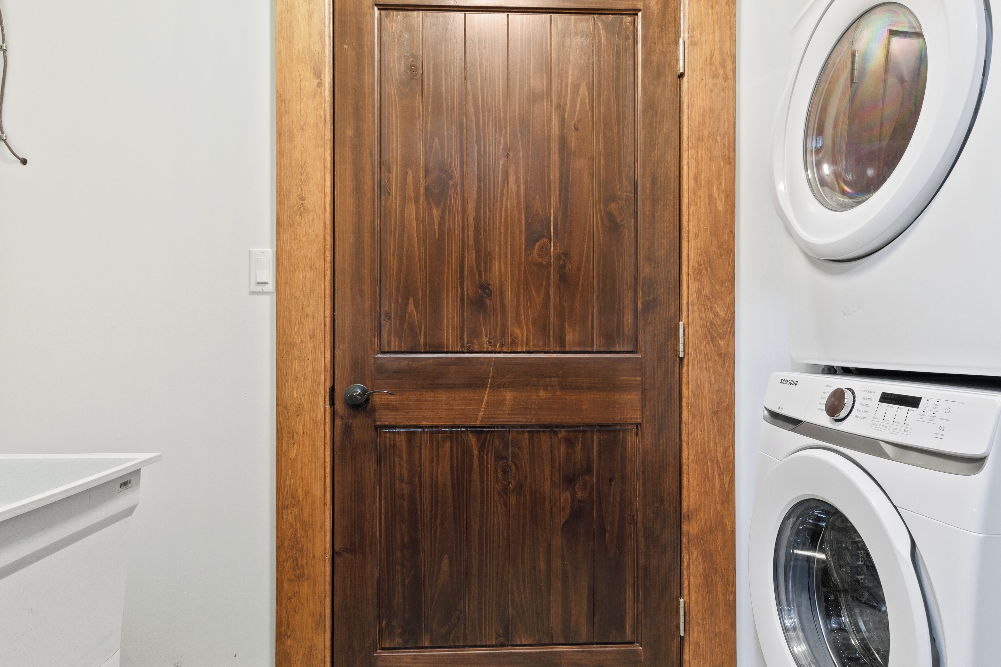 A laundry room with a wooden door, a washing machine, and a dryer.
