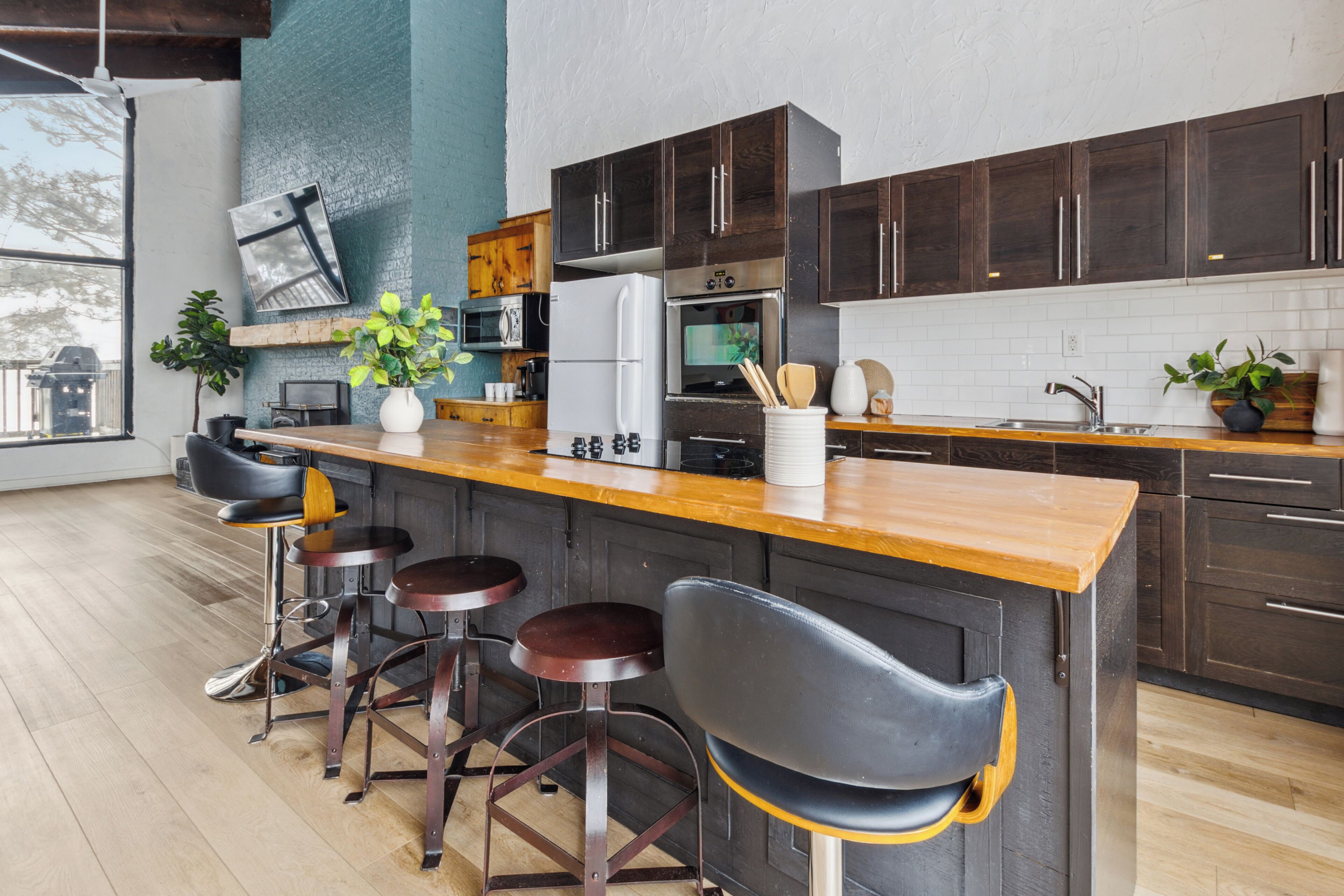 A modern kitchen with dark wood cabinets, a wooden countertop, and bar stools.