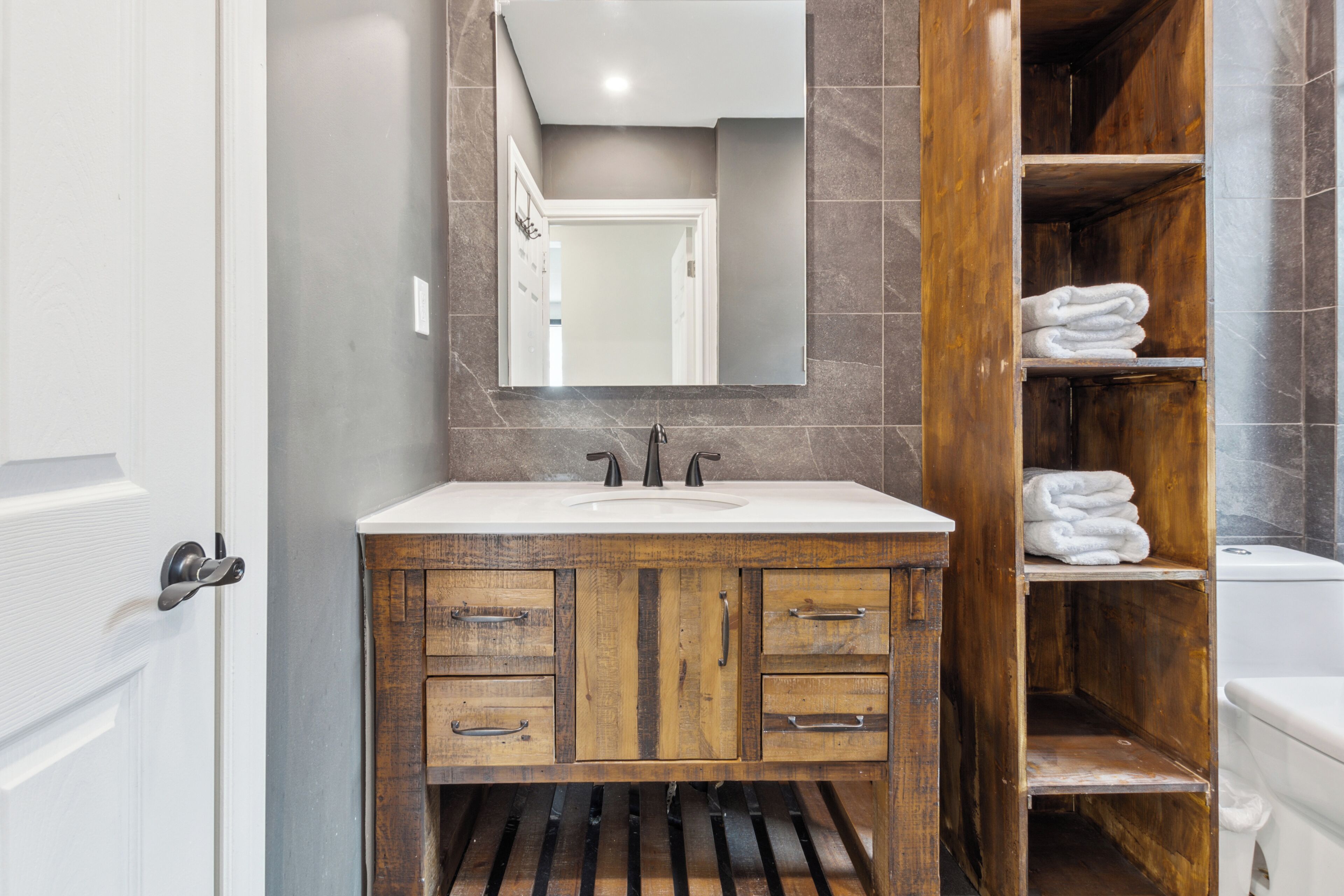 A bathroom with a wooden vanity, a sink, and a mirror.