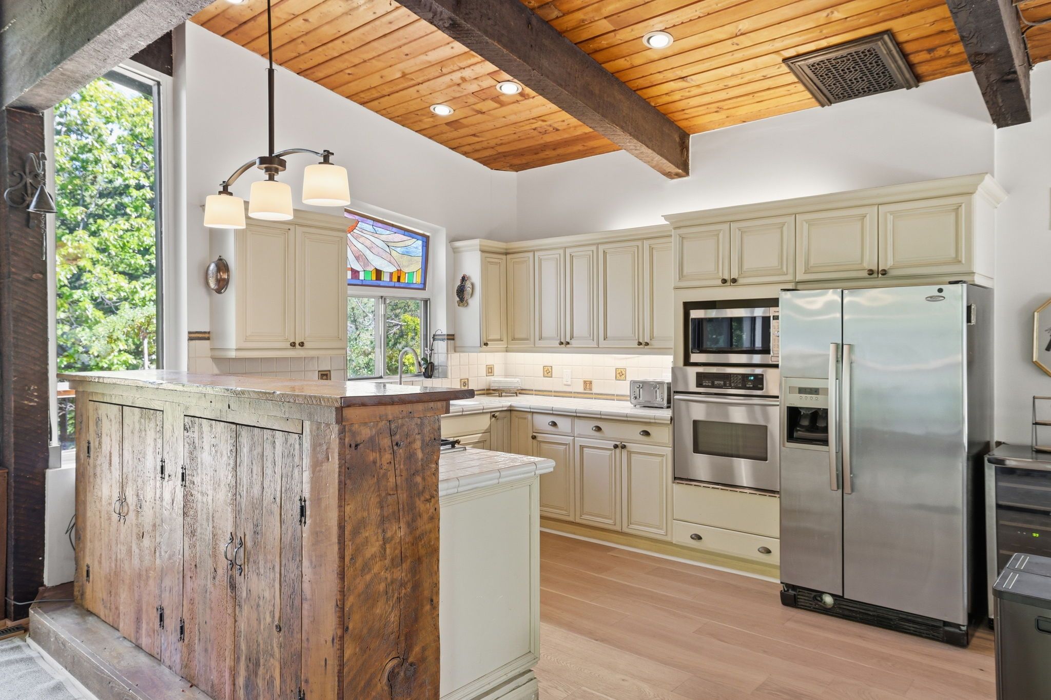 A kitchen with wooden beams, a central island, and stainless steel appliances.