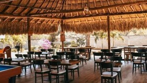 An indoor dining area with thatched roof, wooden tables, and chairs. - Hotel boutique Rancho ton (Santa Marta)