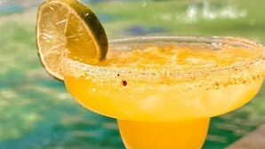 A cocktail with a lime garnish in a glass, placed on a table by a pool. - Hotel boutique Rancho ton (Santa Marta)