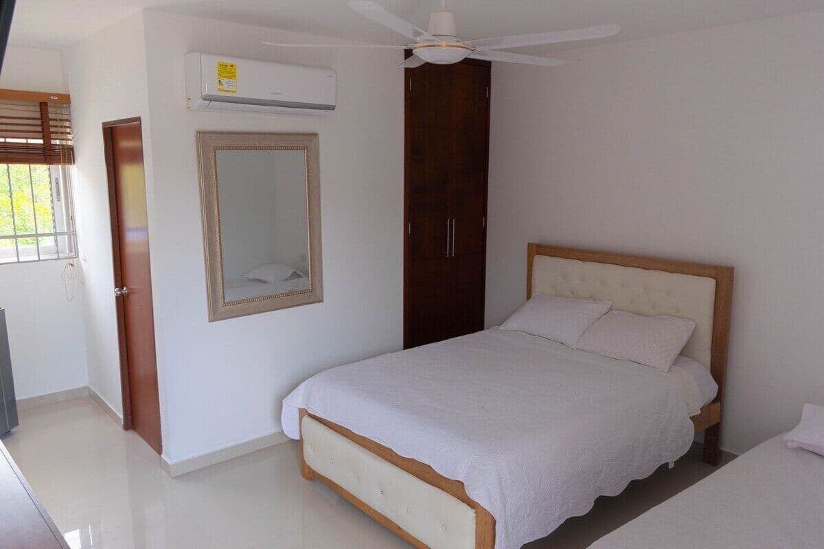 Un dormitorio con cama, armario, espejo y aire acondicionado.