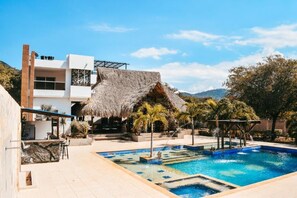 A modern hotel with a pool, a bar area, and a thatched-roof structure. - Hotel boutique Rancho ton (Santa Marta)