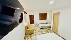 A hotel room with a bed, a sofa, a small table, and a TV. - Hotel boutique Rancho ton (Santa Marta)