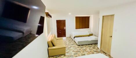 A hotel room with a bed, a sofa, a small table, and a TV.