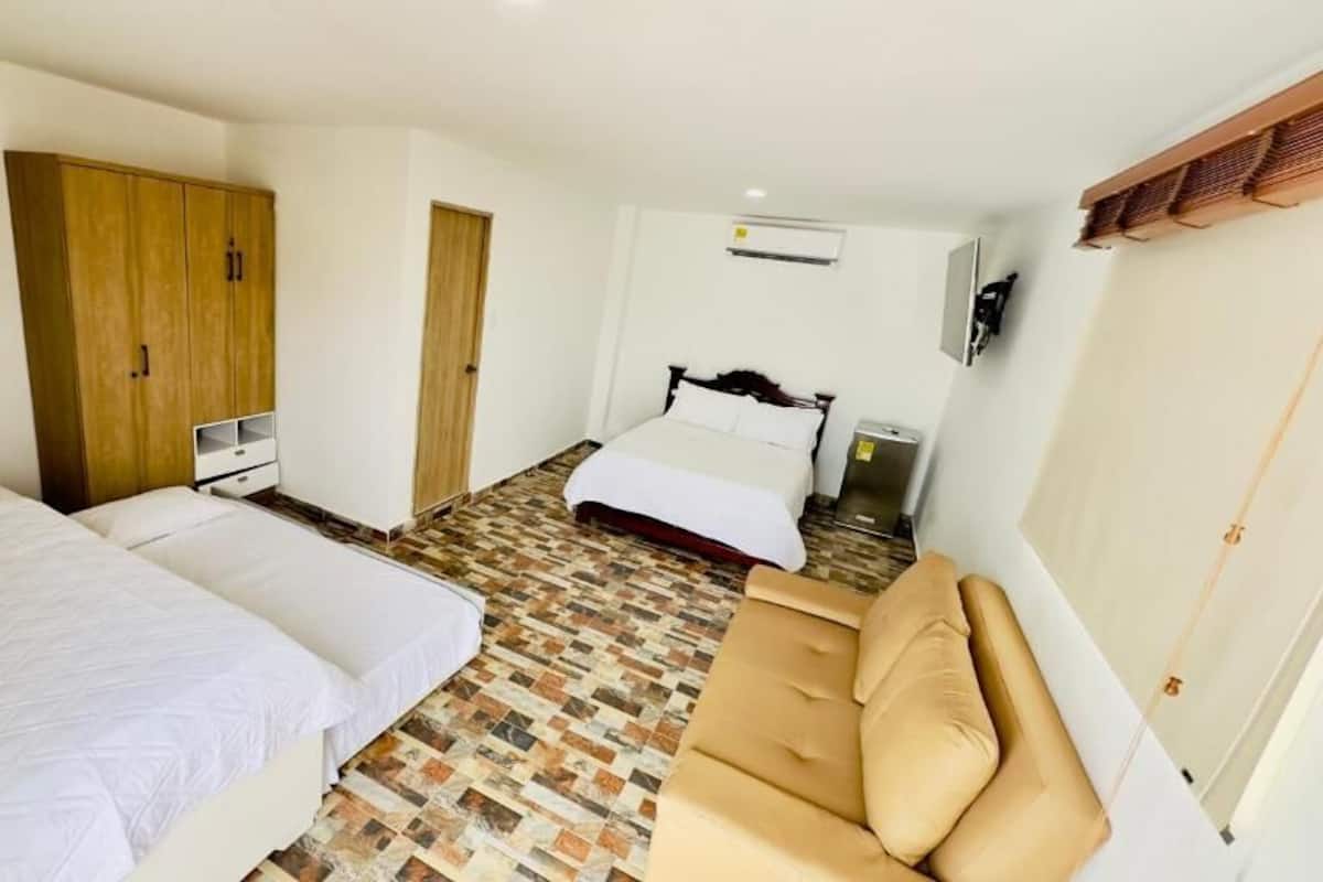 Un dormitorio con dos camas, un armario, un sofá y un televisor.
