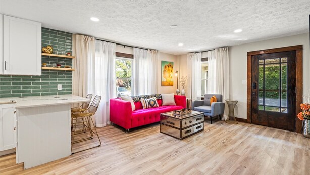 A spacious living area with a kitchen, a red sofa, a blue armchair, and a wooden coffee table. - Downtown Zen - Central Location in Centerville, OH (Centerville)