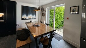 A modern kitchen with a wooden dining table, black chairs, and pendant lighting.