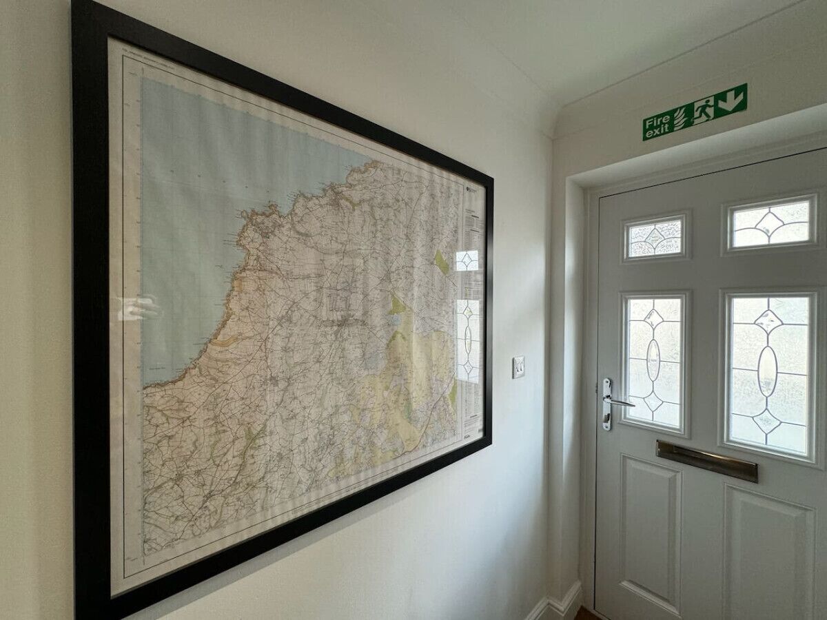 A framed map on a wall, a door with a fire exit sign, and a window with a decorative pattern.