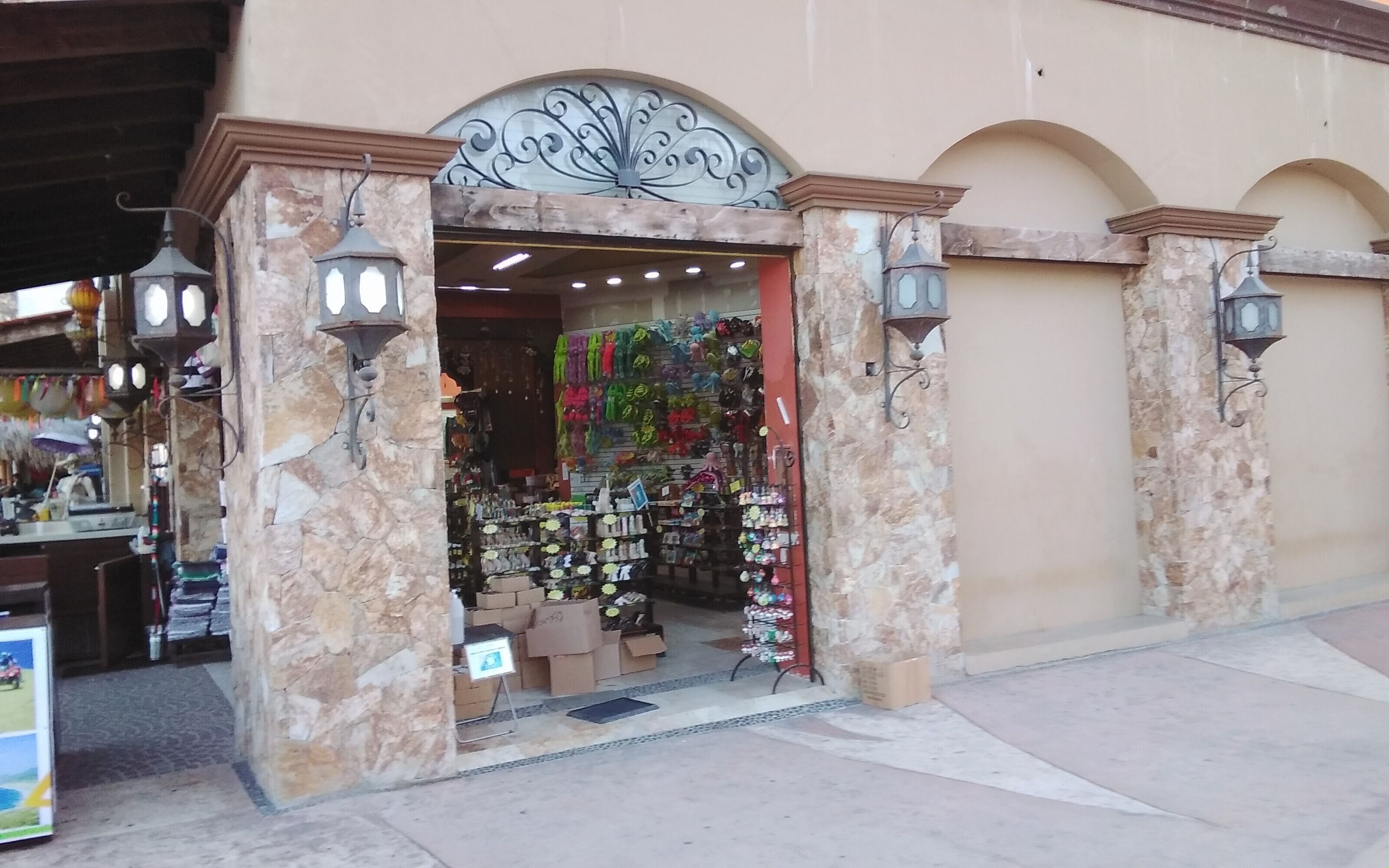 A storefront with a stone facade, ornate metal archway, and hanging merchandise.