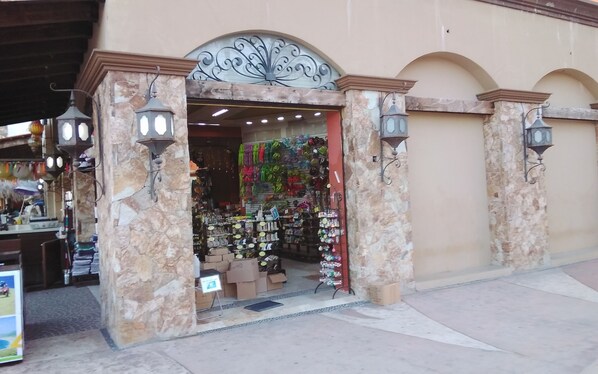 A storefront with a stone facade, ornate metal archway, and hanging merchandise. - Marina Junior Suites (Cabo San Lucas)