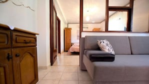 A room with a sofa, a wooden cabinet, and a bed in the background. - Apartments Adriana - One Bedroom Apartment A2+1 (Starigrad-Paklenica)