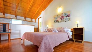 A bedroom with a wooden ceiling, a bed with a pink bedspread, a painting on the wall, and a nightstand with a lamp. - Apartments Adriana - Studio Apartment A2 (Starigrad-Paklenica)