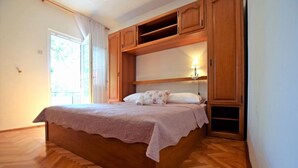 A bedroom with a wooden bed, a nightstand with a lamp, and a window with curtains. - Apartments Adriana - Two Bedroom Apartment A4 (Starigrad-Paklenica)