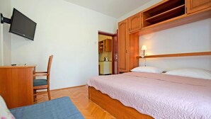 Ein Schlafzimmer mit einem Bett, einem Schreibtisch, einem Stuhl und einem an der Wand befestigten Fernseher.