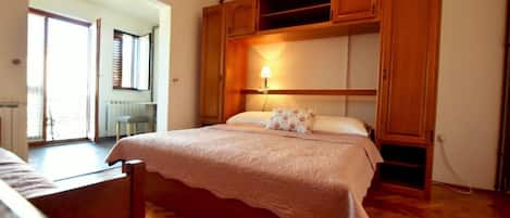 Un dormitorio con una cama de madera, una mesita de noche y un armario empotrado con una lámpara.