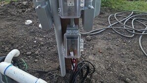 Un cuadro eléctrico con varios cables y un conducto adherido a un poste de utilidad.