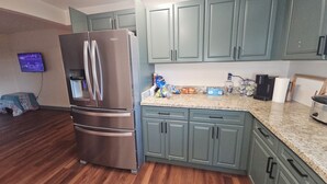 Una cocina con refrigerador de acero inoxidable, encimeras de granito y gabinetes color turquesa.