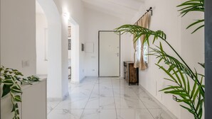 A hallway with white walls, a marble floor, and a wooden cabinet. - Magic Seaside Apartment (Rosignano Marittimo)