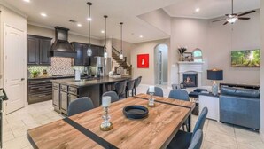 A spacious kitchen with dark cabinets, a wooden island, and pendant lighting.