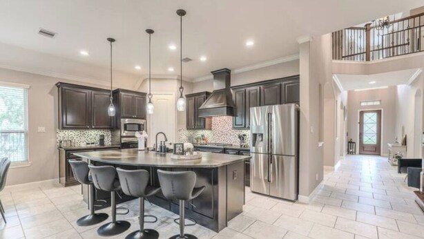 A spacious kitchen with a central island, stainless steel appliances, and pendant lighting.