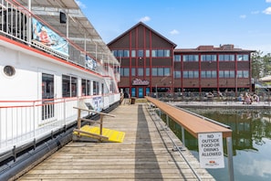 A dock with a boat, a building with a sign reading "Dockside," and a sign prohibiting outside food or drinks. - The Lodges at Breezy Point (Breezy Point)
