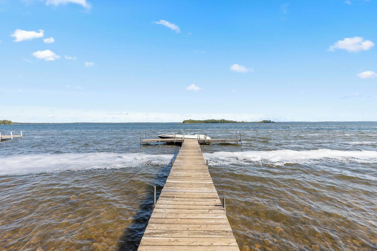 A wooden pier extending into calm water with a small island in the distance.