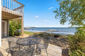 A wooden deck with a metal table and chairs overlooking a lake with boats. - The Lodges at Breezy Point (Breezy Point)