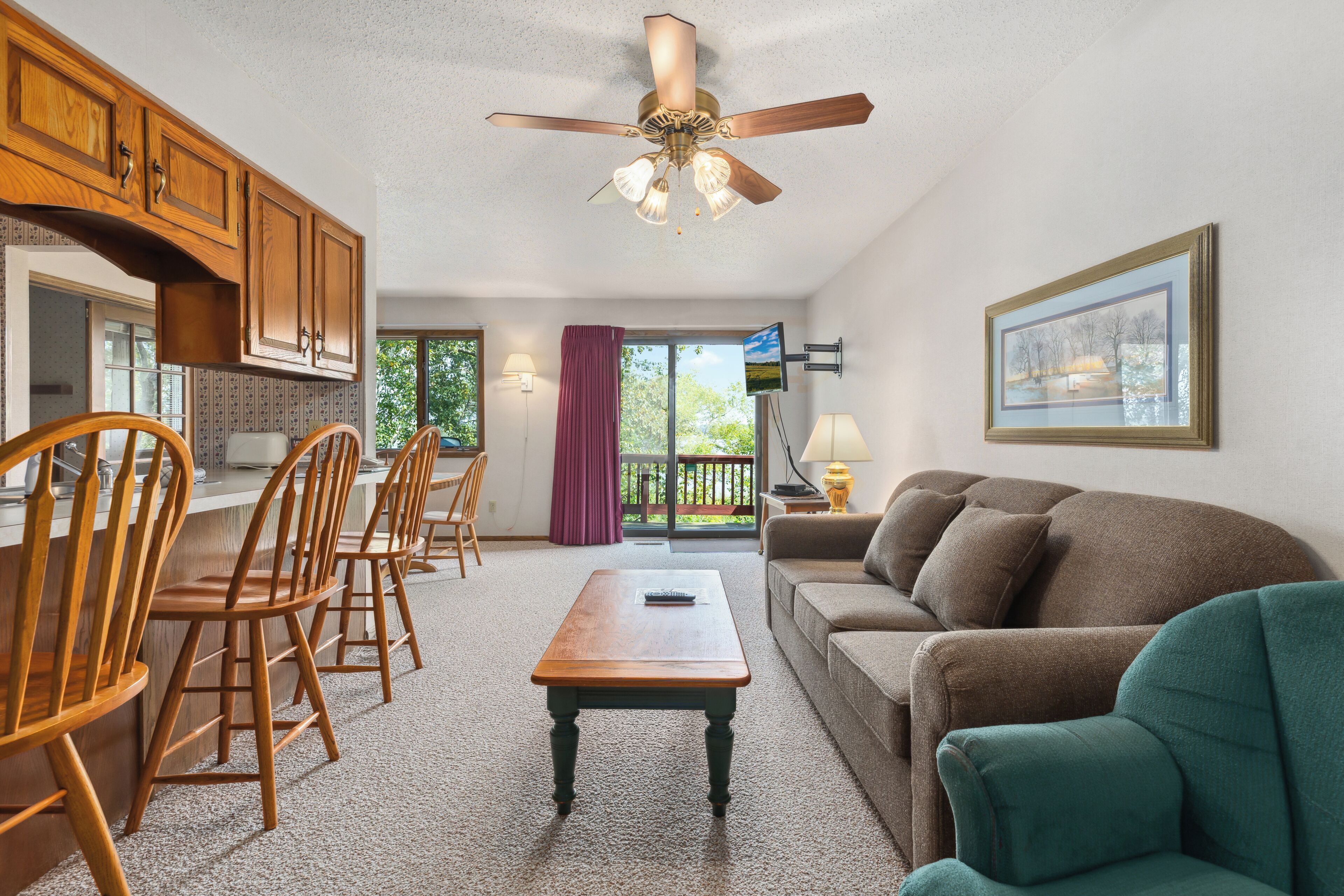 A spacious living area with a wooden dining set, a sofa, and a ceiling fan.
