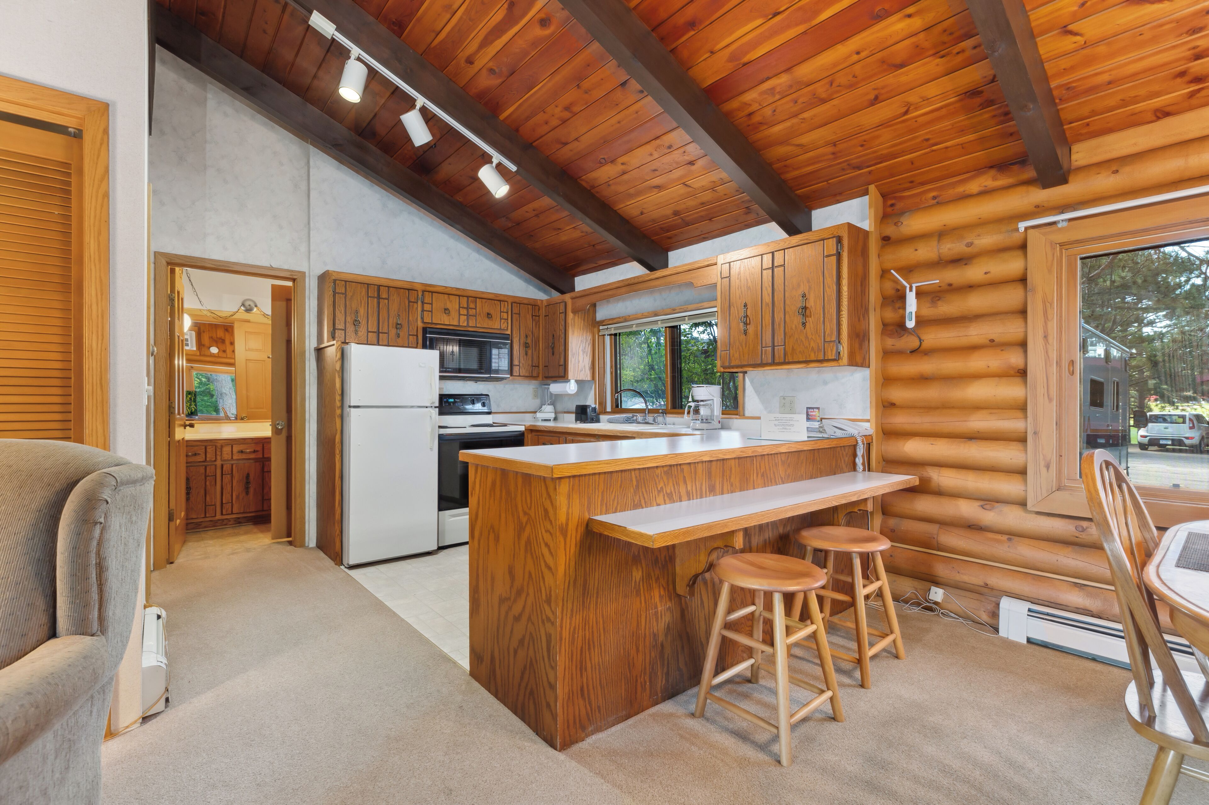 A log cabin kitchen with a central island, wooden cabinets, and a dining area.