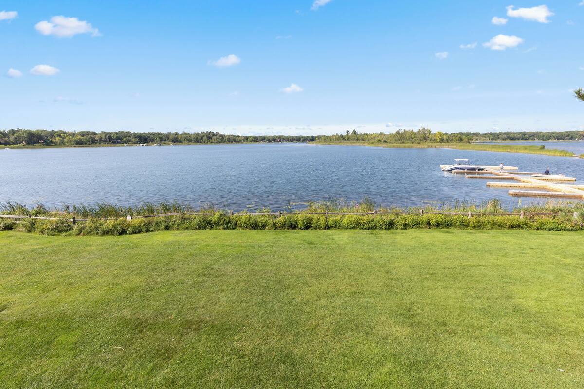 A lake with a dock and grassy area in the foreground.