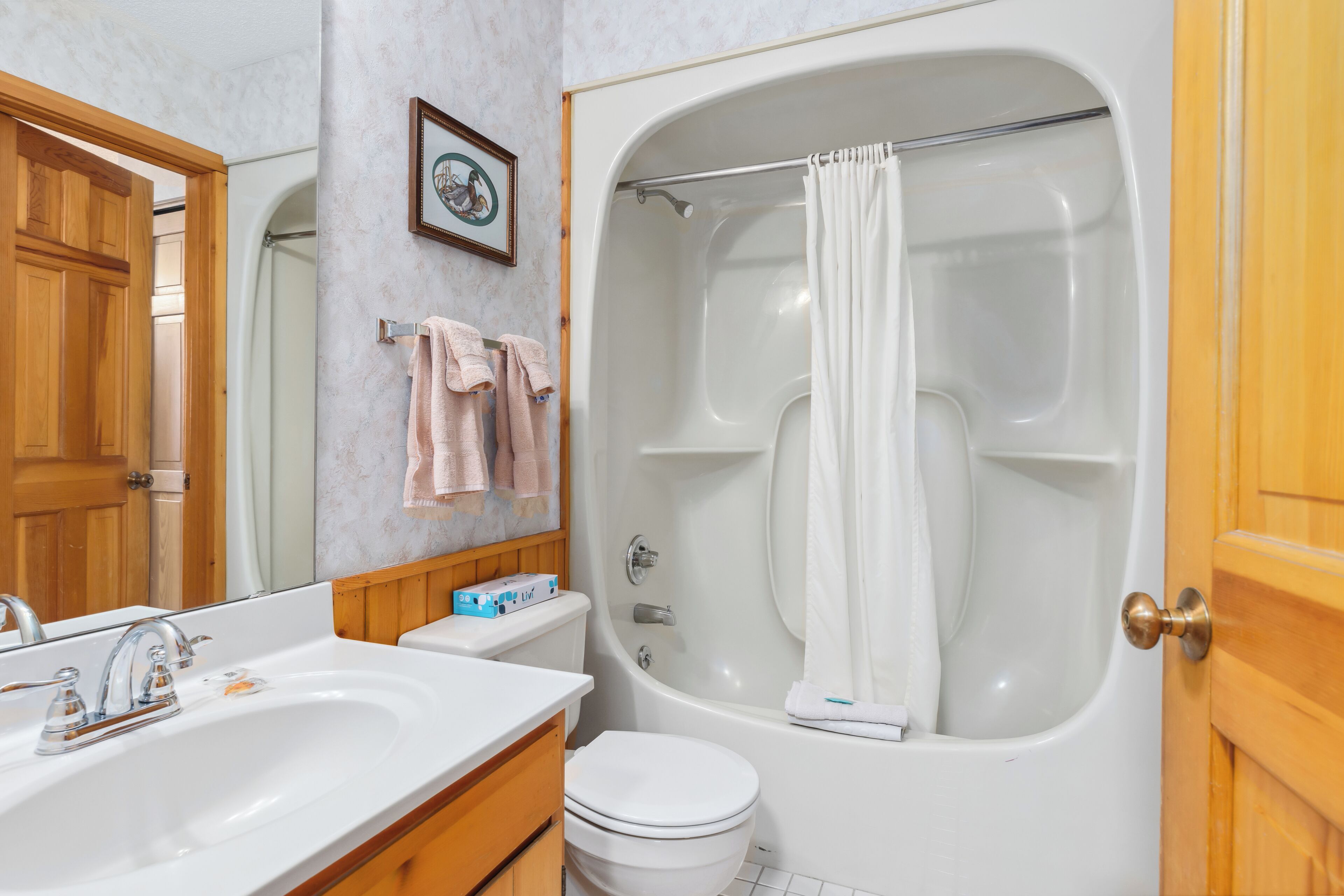 Une salle de bain avec une baignoire, des toilettes, un lavabo et des meubles en bois.