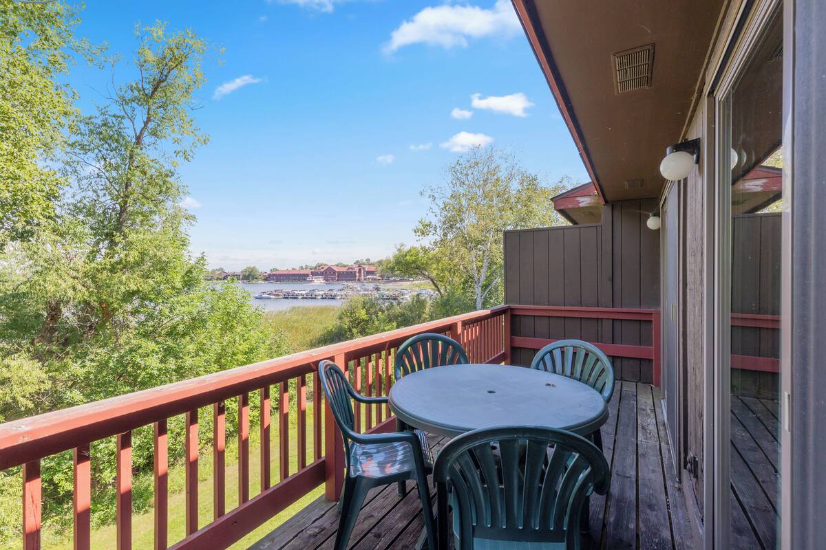 A wooden deck with a red railing, a round table, and four chairs.