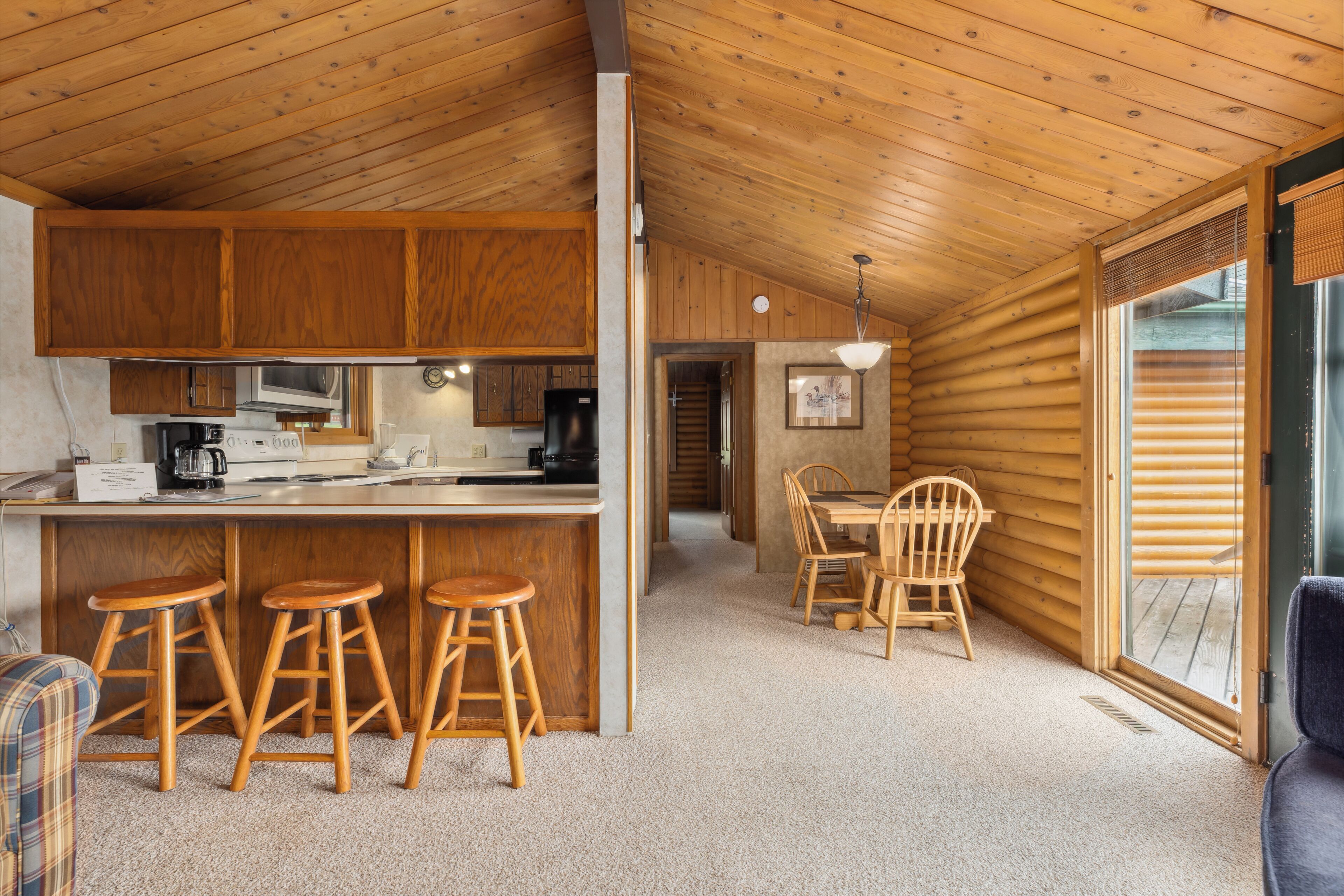 A log cabin interior with a kitchen, dining area, and a large window.