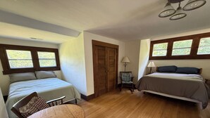 Una habitació amb dos llits, una taula de fusta i una cadira.