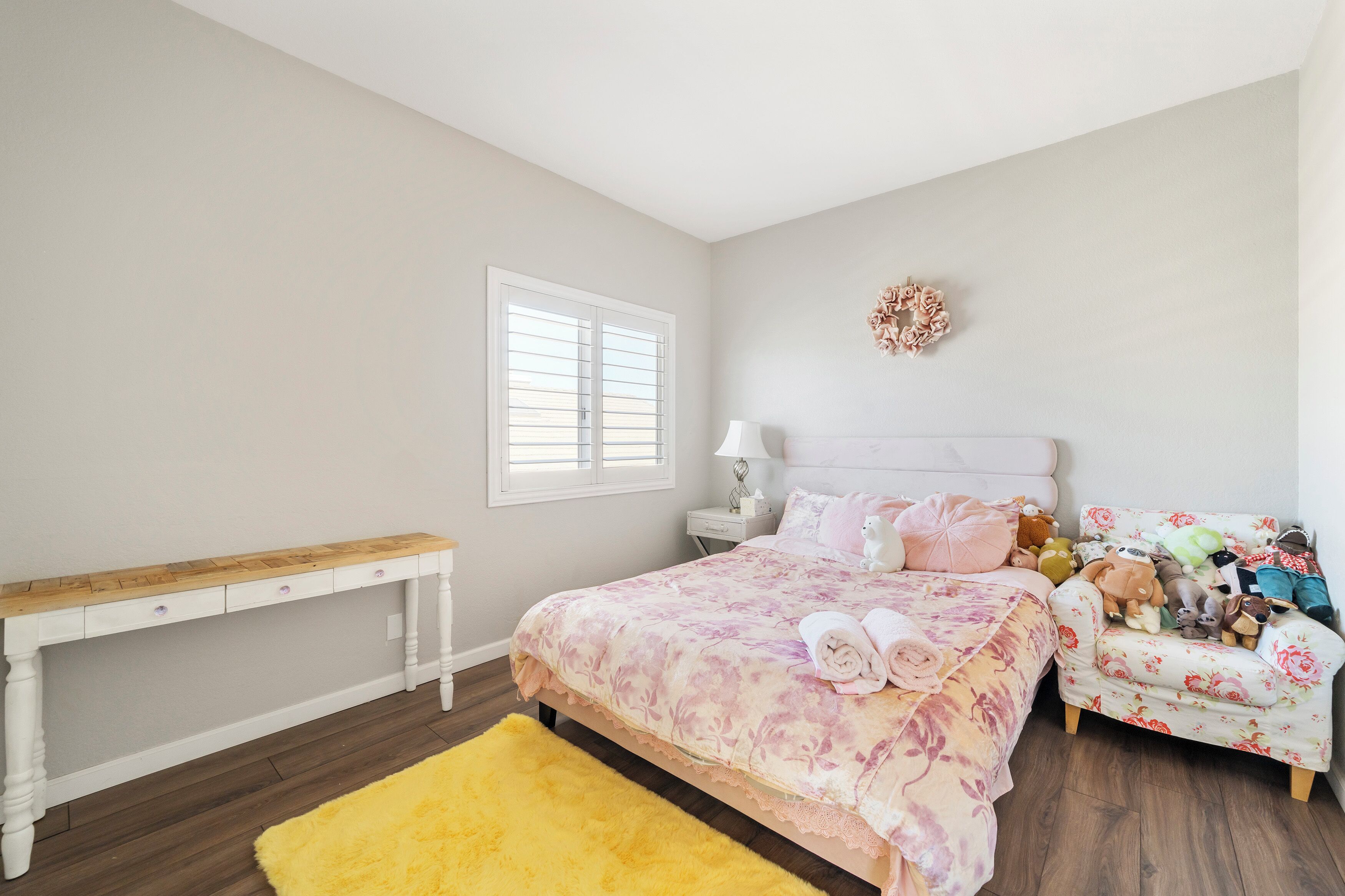 Um quarto com cama, mesa de cabeceira e um pequeno sofá.